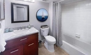 A bathroom with a white sink, a toilet, a mirror, and a shower curtain. - Quiet South-End Condo w Marina Access Bayfront (Fort Myers Beach)