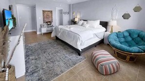 Une chambre à coucher avec un lit, une chaise, un tapis, une télévision et un bureau.
