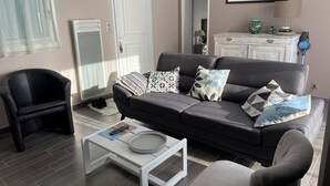 Ein Wohnzimmer mit grauem Sofa, schwarzem Sessel, weißem Couchtisch und grauem Sessel.