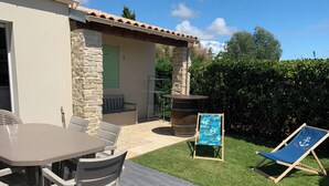 Eine Terrasse mit Tisch und Stühlen, eine kleine Sitzecke und ein Liegestuhl.