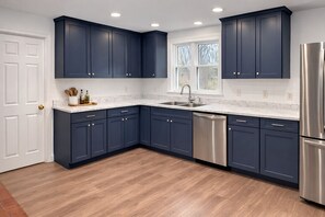 A kitchen with dark blue cabinets, a stainless steel refrigerator, and a dishwasher.