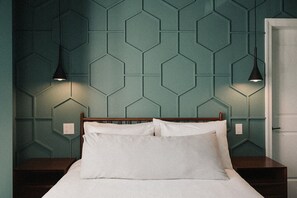 A bedroom with a bed, two bedside lamps, and a wall with a geometric pattern. - Hotel Morado (Chilliwack)