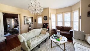 A living room with a chandelier, two sofas, a coffee table, and large windows. - Near The Baseball Hall of Fame, Glimmerglass Opera and Dream Park Baseball Camp (Cherry Valley)