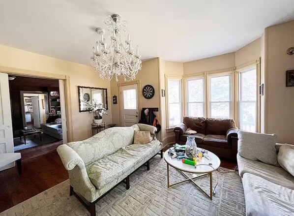 A living room with a chandelier, two sofas, a coffee table, and large windows.