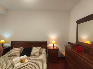 Ein Hotelzimmer mit Bett, Nachttischen, einem Schminktisch und einem Spiegel.