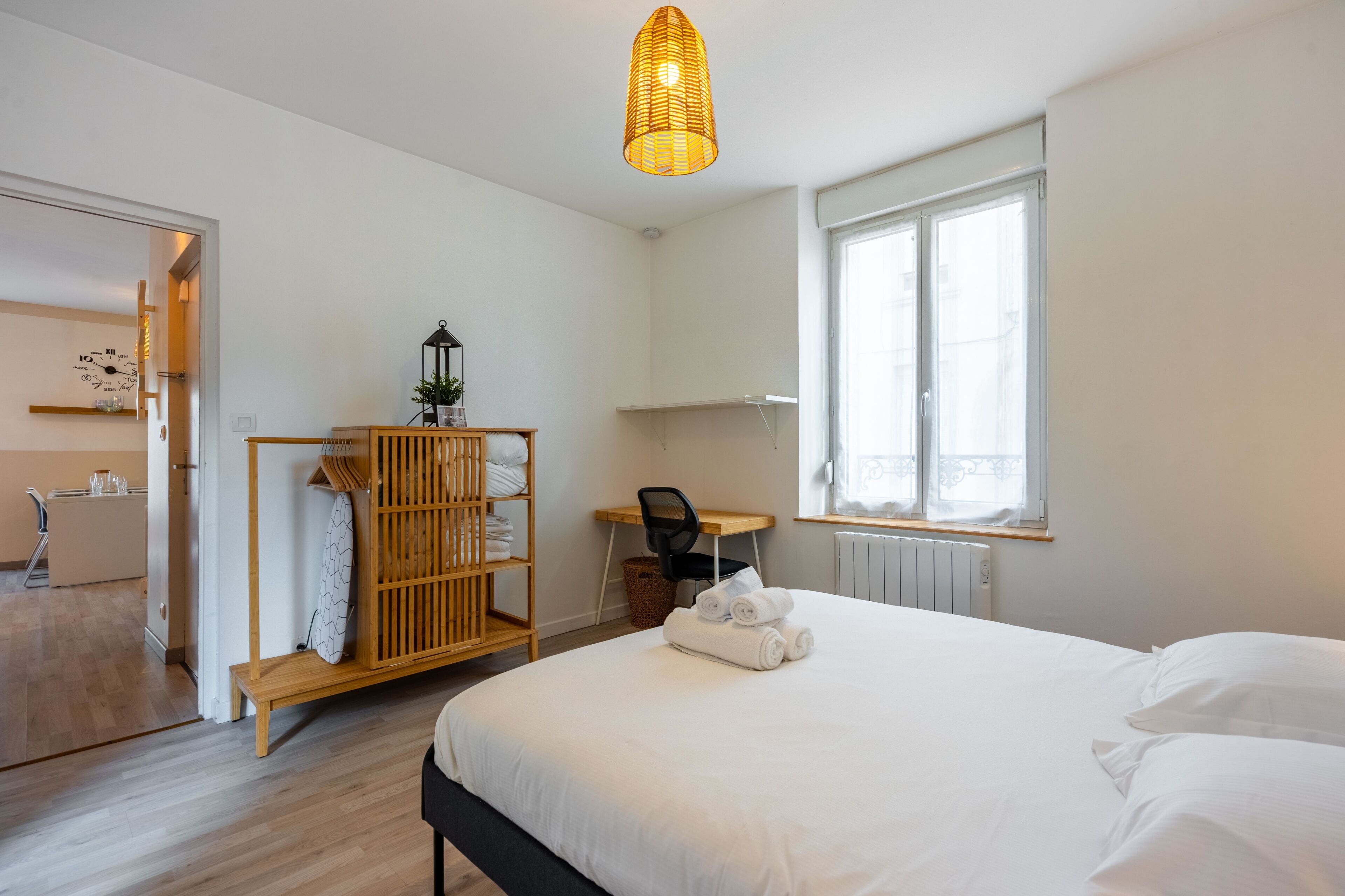 Une chambre d’hôtel équipée d’un lit, d’un bureau, d’une chaise, d’une armoire et d’une fenêtre donnant sur un paysage agréable.