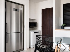A compact kitchen with a stainless steel refrigerator, a microwave, a small refrigerator, a glass table, and a black chair. - Cosy apartment in the center of the island - View of the Mornes and the bay! (Fort-de-France)