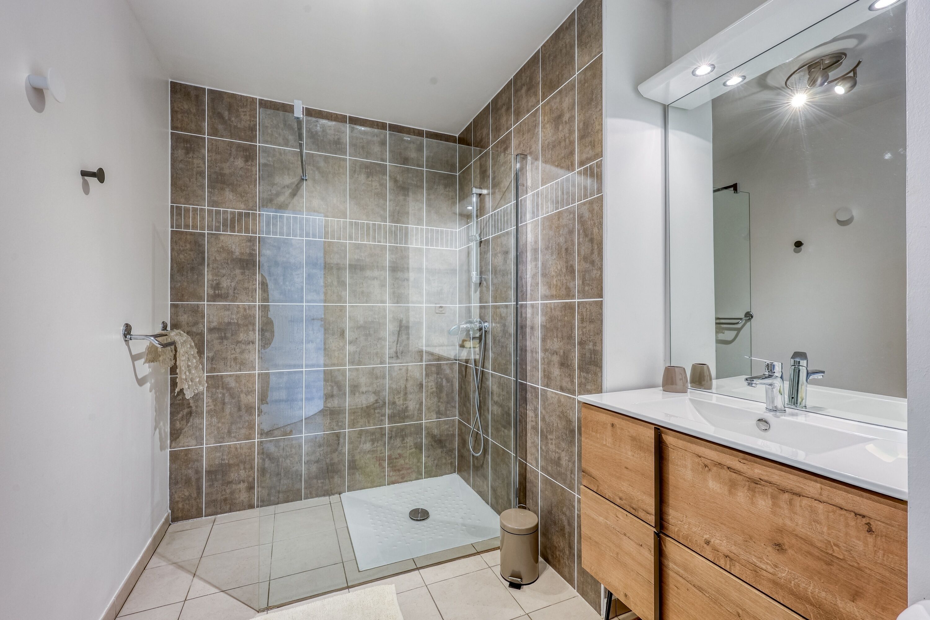 A modern bathroom with a shower, a sink, and a mirror.