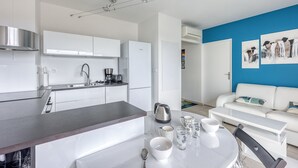 A modern kitchen with white cabinets, a stainless steel range hood, and a dining area with a white table and chairs. - La Terrasse de La Ciotat - climatisé, proche plage (La Ciotat)