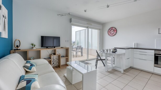 A modern living room with a sofa, a coffee table, a TV, and a kitchen area with a dining table and chairs. - La Terrasse de La Ciotat - climatisé, proche plage (La Ciotat)