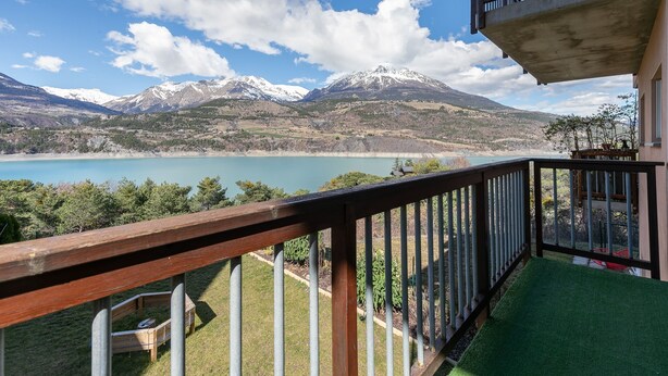 Un balcon avec vue sur les montagnes et un lac.