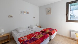 Une chambre avec deux lits, une table de chevet, une lampe et une fenêtre.