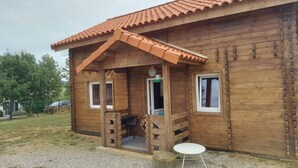 Una cabaña de madera con techo de tejas, un porche y una pequeña mesa.