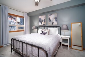 Ein Schlafzimmer mit einem Bett, Nachttischen, einem Spiegel und Kunstwerken an der Wand.