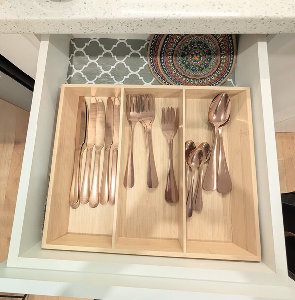 A drawer with neatly organized cutlery including knives, forks, and spoons.