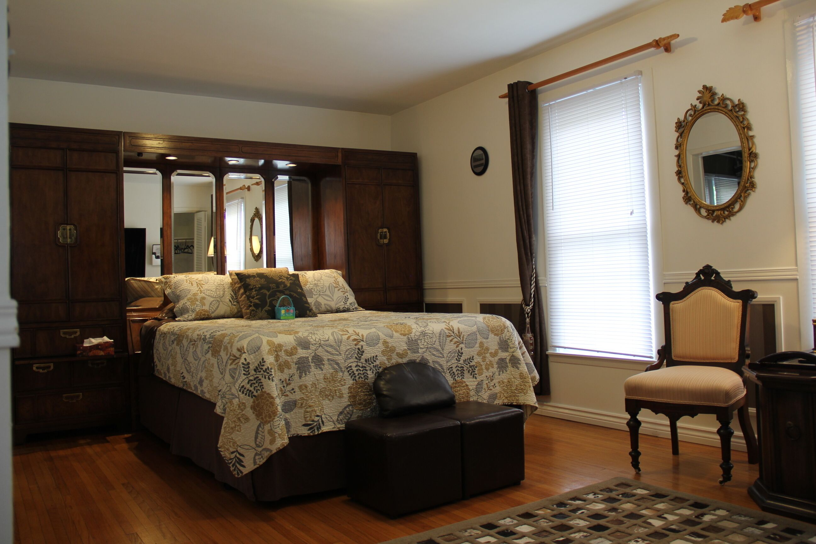 A bedroom with a large bed, a dresser, a chair, and a window with curtains.