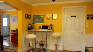 A room with yellow walls, a white door labeled 'PRIVATE,' a desk with a laptop, two white bar stools, and a red cabinet. - Cozy House located close Skylon Towery, Falls view Casino & Horseshoe Falls (Niagara Falls)