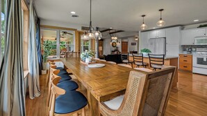 A spacious kitchen with a long wooden table, modern appliances, and pendant lighting. - Brand New Lakefront Oasis: Private Dock & boat launch, Kayaks, Hot Tub (Sevierville)