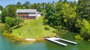 A two-story house with a deck, a dock, and a pond. - Brand New Lakefront Oasis: Private Dock & boat launch, Kayaks, Hot Tub (Sevierville)