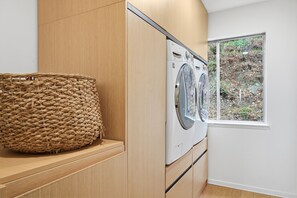 A laundry room with a washing machine, wooden cabinets, and a large woven basket.