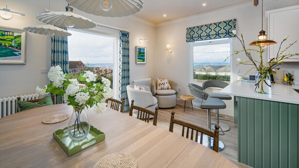 Una cucina moderna con zona pranzo, vista all'esterno e un'ampia finestra con tende.