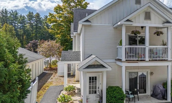 A two-story house with a balcony, a covered patio, and a front door.