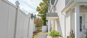 A narrow pathway leading to a house with a white exterior, a covered porch, and a mailbox.