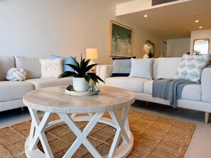 Un salon avec une table basse ronde, une plante en pot et un canapé agrémenté de coussins décoratifs.
