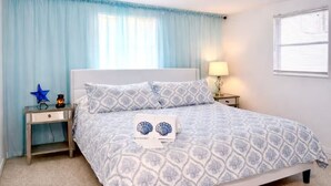 Une chambre à coucher avec un lit, une table de chevet, une lampe et une fenêtre.