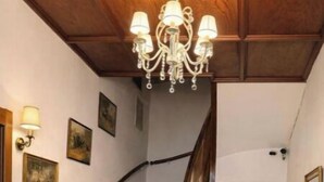 Una scala in legno con un lampadario, un estintore e un tappetino d'ingresso.