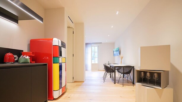 A modern kitchen with a colorful refrigerator, a dining area with a table and chairs, and a built-in wine cooler. - Villa Amelia (Orta San Giulio)