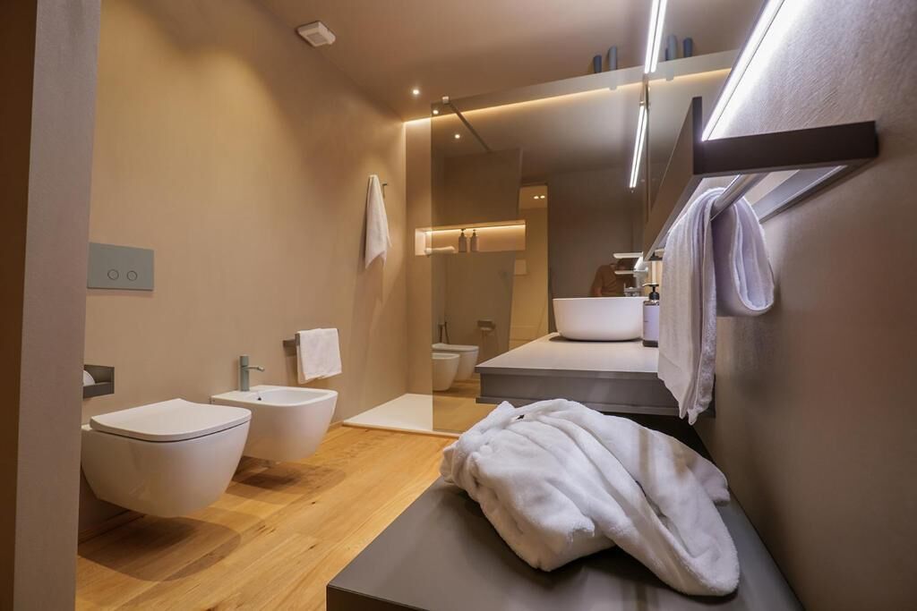 Ein modernes Badezimmer mit Holzboden, einer weißen Badewanne, einer weißen Toilette und einem Waschbecken.