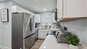 Una cocina moderna con electrodomésticos de acero inoxidable, armarios blancos, horno integrado y una encimera con un tostador.