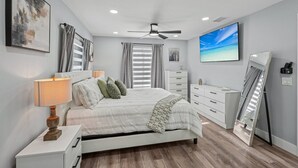 Un dormitorio con cama, mesita de noche, lámpara, cómoda y un espejo grande.
