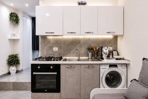 A compact kitchen with a gas stove, oven, sink, and washing machine. - La Casetta di Gelsomina | Centro Storico | 4 pax (Napoli)