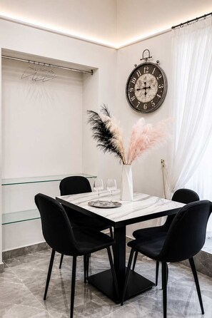 A dining area with a marble table, black chairs, a clock, and pampas grass decorations. - La Casetta di Gelsomina | Centro Storico | 4 pax (Napoli)