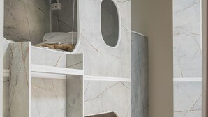 Una cama individual en literas con ventilador incorporado, un espacio reducido cerrado y un baño con ducha.
