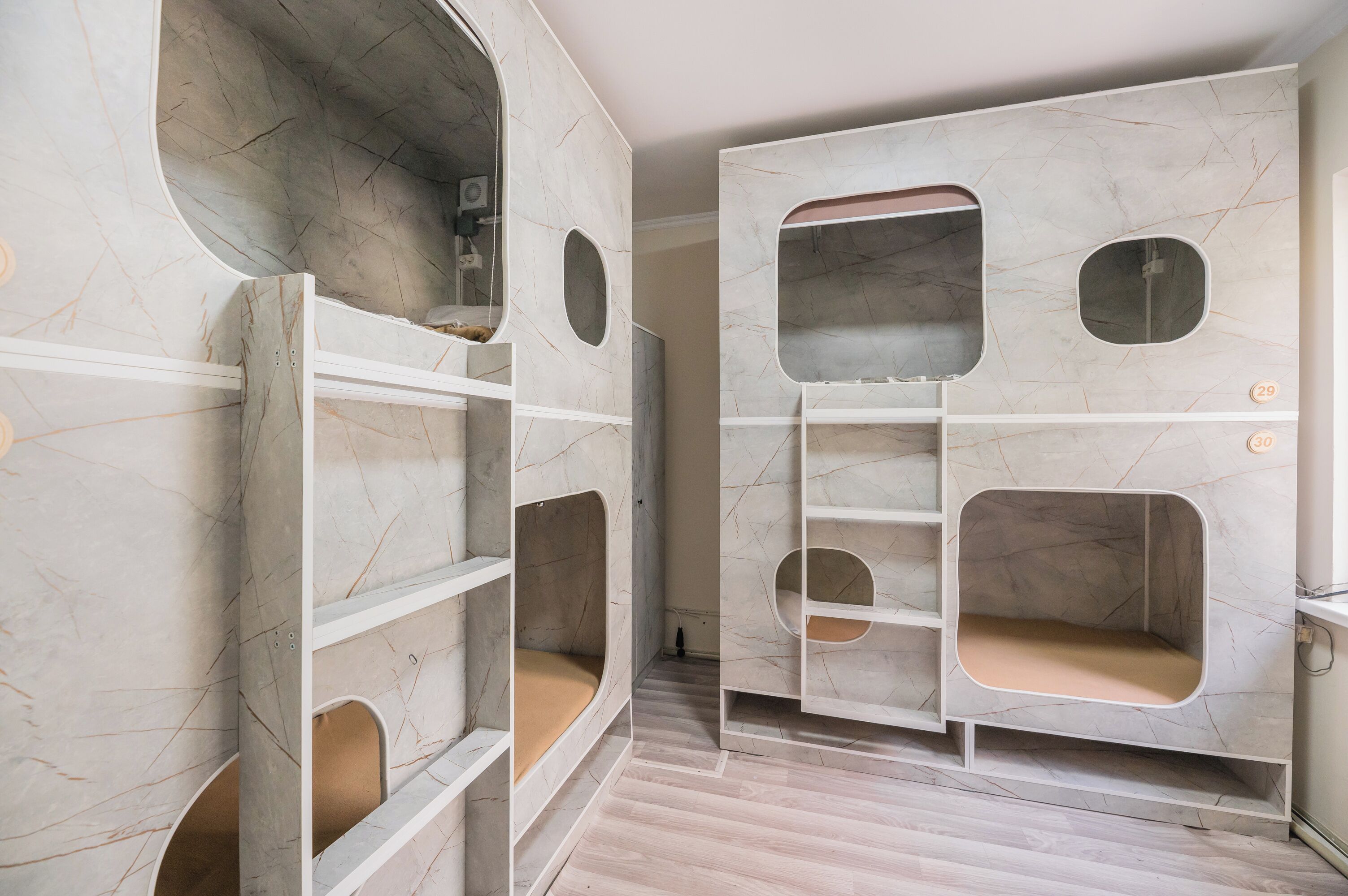 Una habitación con un diseño moderno y singular, que incluye estanterías empotradas con cortes circulares y un acabado similar al mármol.