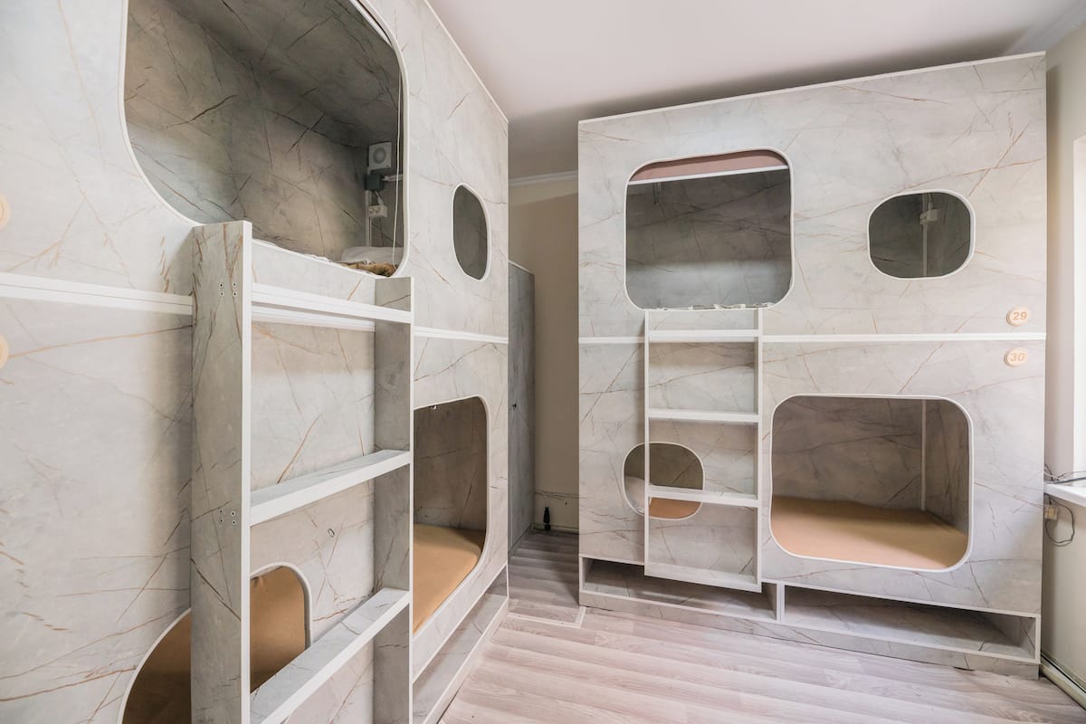 Una habitación con un diseño moderno y singular, que incluye estanterías empotradas con cortes circulares y un acabado similar al mármol.