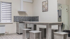 Una cocina moderna con encimera de mármol, armarios blancos y un amplio ventanal con persianas.