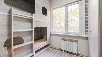 A room with a built-in shelving unit, a window with a view of trees, and a radiator.