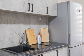 A kitchen with a sink, a cutting board, a bottle of dish soap, and a refrigerator. - Arch Hostel – Male Guests Only (Almaty)