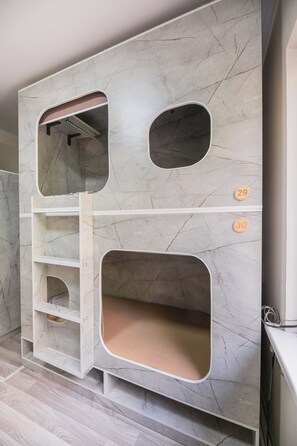 Una habitación con cama doble empotrada, compartimentos de almacenamiento y una pequeña zona de estar.