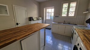 Eine Küche mit weißen Schränken, einer Holzausziehtafel, einer Spüle und einem Fenster.