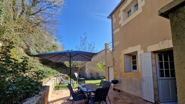 Eine Terrassenausstattung mit Tisch, Stühlen, einem Grill und einer Steinwand.