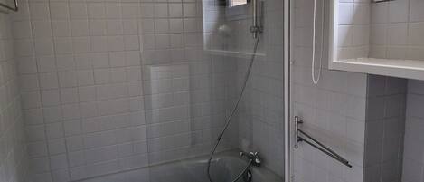 A bathroom with a glass-enclosed shower, a bathtub, and a toilet.
