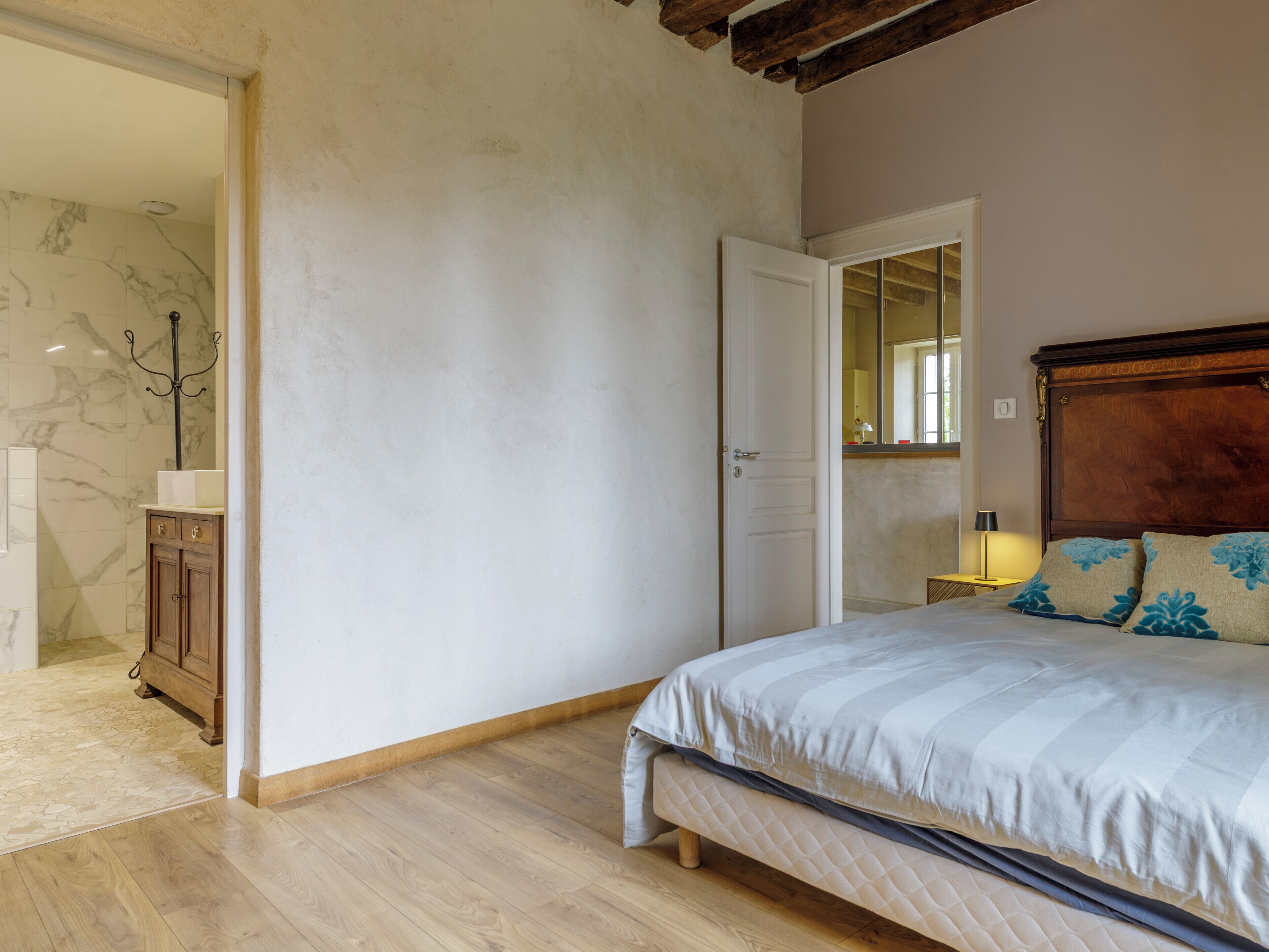 Ein Schlafzimmer mit einem hölzernen Bett, einer weißen Tür, einem Spiegel und einem Holzboden.