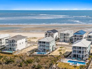 Ein Küstenhotel mit mehreren Gebäuden, einem Schwimmbad und Blick auf den Strand.