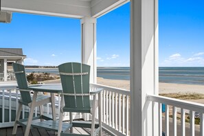 A porch with two green Adirondack chairs, a white railing, and a view of the beach and ocean. - Into The Mistic, Ocean Isle Beach (Ocean Isle Beach)