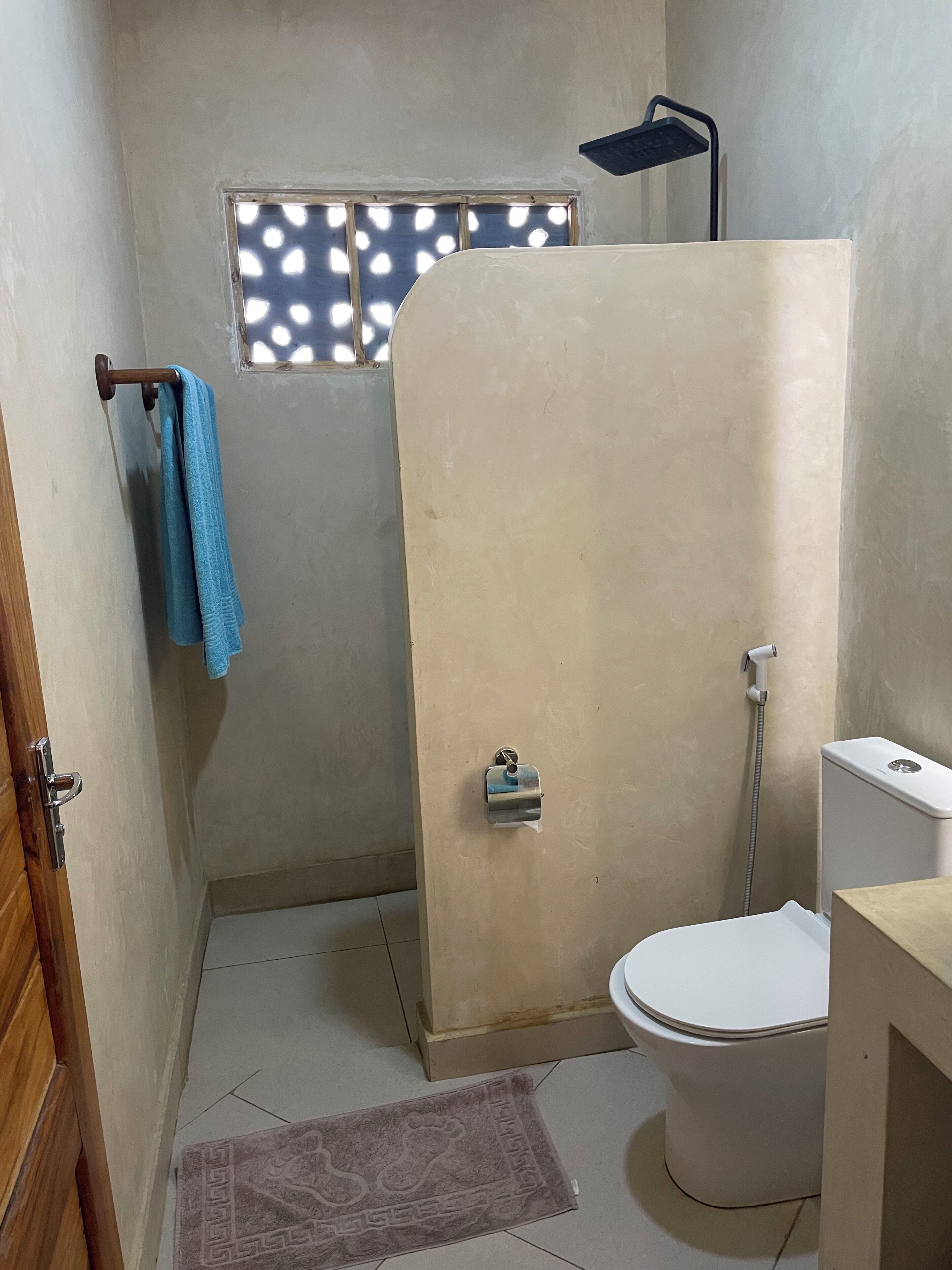 A bathroom with a shower, toilet, and a towel rack.